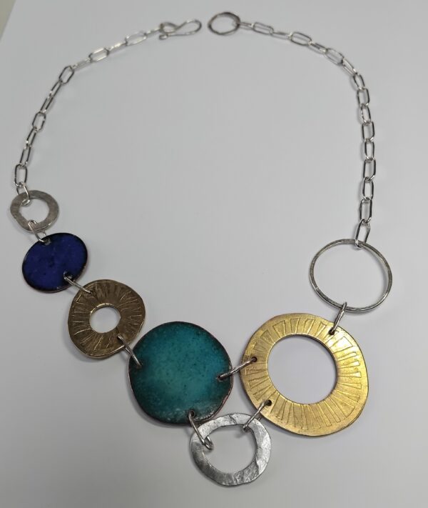 Etched brass, enamelled copper, and eco silver circles linked together forming a constellation. with a paperclip style silver chain.