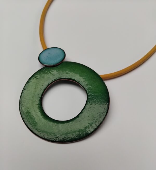 Green enamelled circle with next to small sky blue circle on a yellow leather cord.