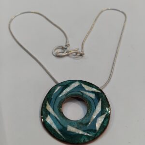 enamelled copper circle with layers of transparent enamel with embedded silver leaf shapes.